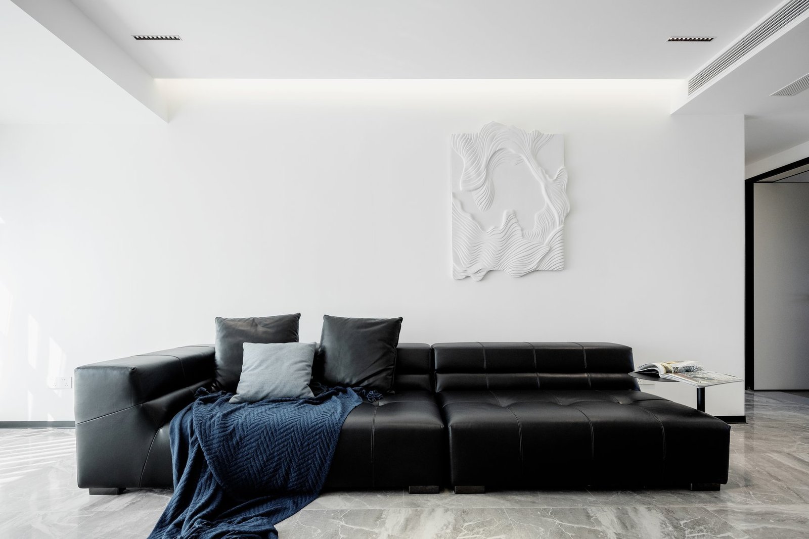 Black leather sofa and sculptural wall art in the completed living room