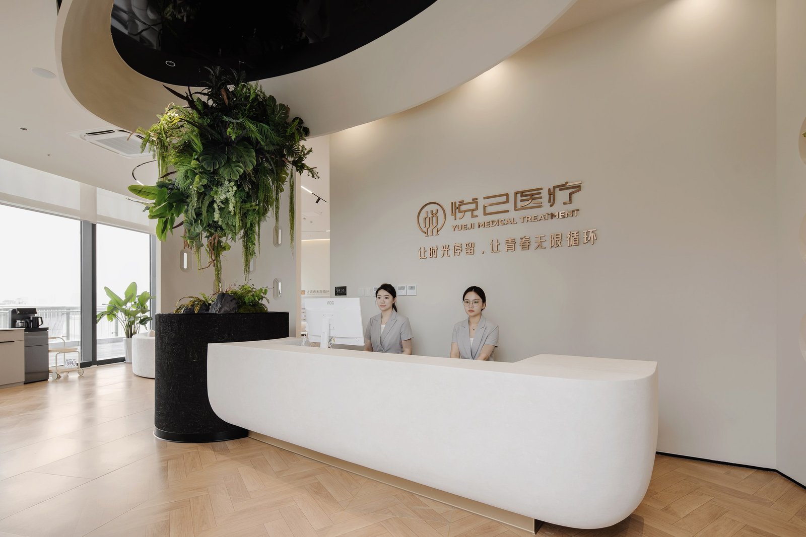 Curved white reception desk and integrated planting beneath a sculptural ceiling